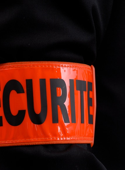 Bras portant un brassard orange brillant avec l'inscription noire SECURITE.